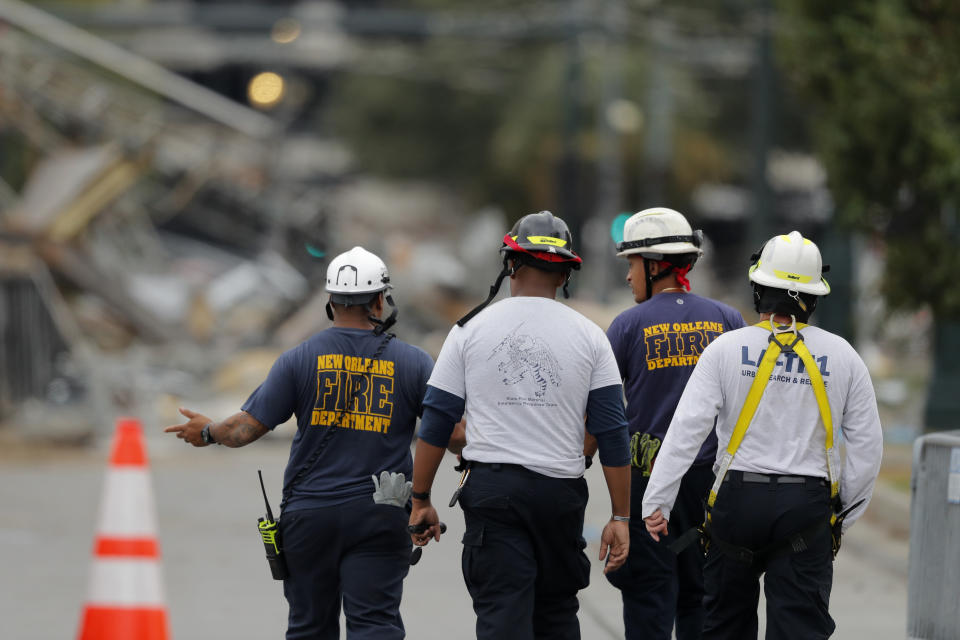 New Orleans Fire Department personnel walk toward the scene of the Hard Rock Hotel in New Orleans, Wednesday, Oct. 16, 2019. New Orleans officials say the chances of a missing worker's survival after the collapse are diminishing, and they have shifted their efforts from rescue to recovery mode. News outlets report Fire Department Superintendent Tim McConnell says they shifted Wednesday ahead of a possible tropical storm. McConnell says chances of the missing worker's survival will be considered nearly "zero" if no sign of him turns up by Wednesday night. (AP Photo/Gerald Herbert)