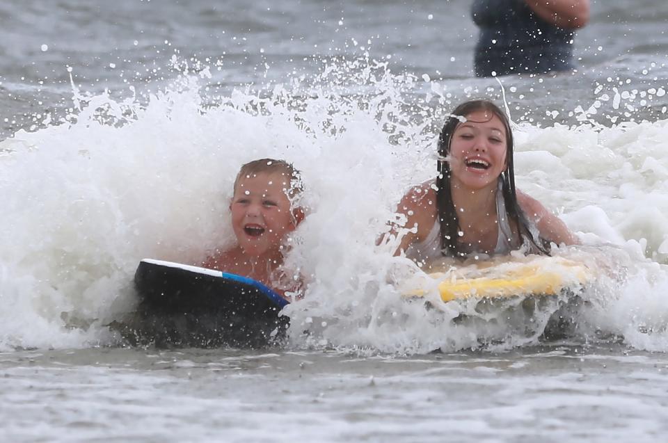 Matthew and Kylie Rodenberg of White Hall, Arkansas, enjoy their first beach vacation as they ride the waves on boogie boards Tuesday afternoon at Tybee Island.