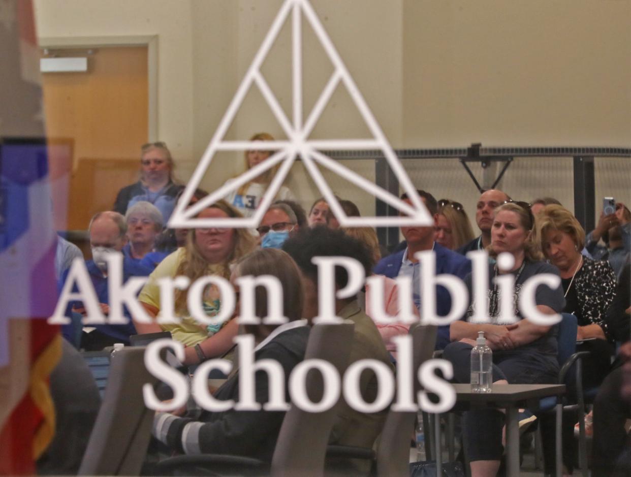 Teachers, staff and audience members are reflected in a mirrored window in the boardroom at Monday's Akron school board meeting