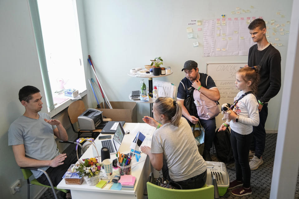 A family from Mariupol speaks with a volunteer, left, after arriving in Estonia from Russia with the help of volunteers on both sides of the border in Narva, Estonia, Thursday, June 16, 2022. An Associated Press investigation has found that many Ukranian refugees are forced to embark on a journey into Russia. (AP Photo)