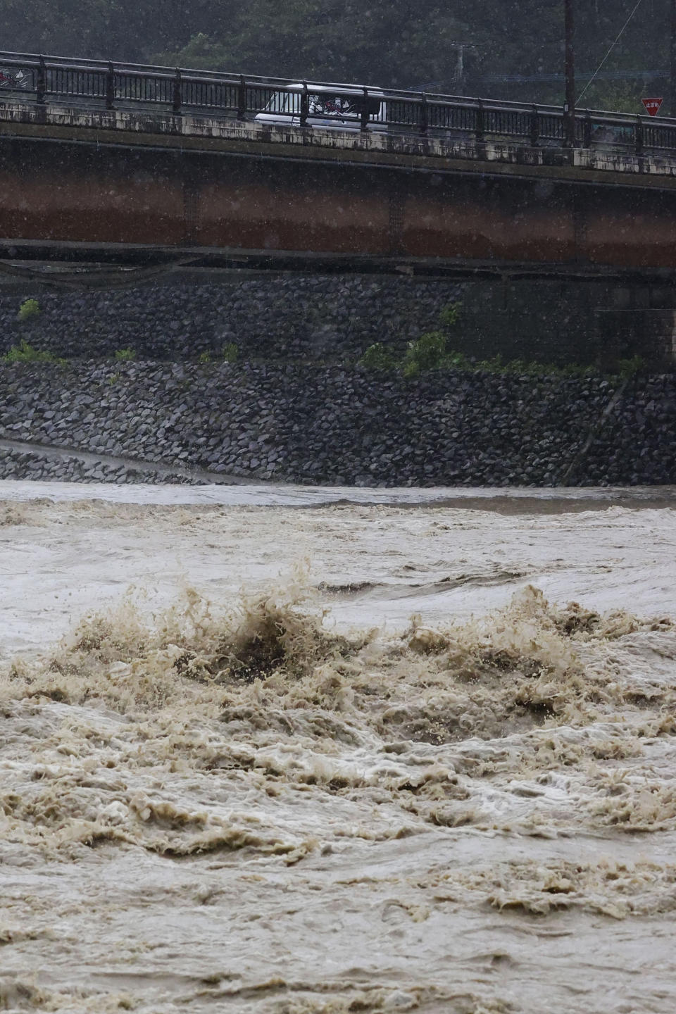 The swollen Kuma River is seen after heavy rains in Kuma village, Kumamoto prefecture, southern Japan as a powerful typhoon hits the area on Monday Sept. 19, 2022. Powerful Typhoon Nanmadol slammed ashore in southern Japan on Sunday as it pounded the region with strong winds and heavy rain, causing blackouts, paralyzing ground and air transportation and prompting the evacuation of thousands of people. (Kyodo News via AP)