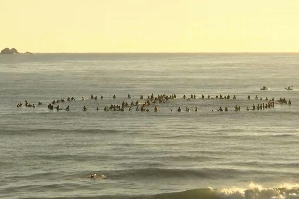 In this image made from video, surfers form a cancel symbol in the water of Byron Bay, Australia, Tuesday, April 20, 2021. Around 100 surfers paddled to sea to form a cancel symbol in the hope that Netflix will can the series about social media influencers. Angry Byron Bay locals are protesting the filming of a reality television series that some fear will damage the reputation of their trendy Australian tourist town. (Australian Broadcasting Corporation via AP)