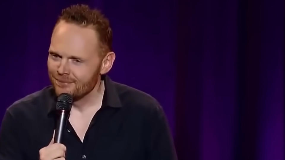 A close up of Bill Burr holding a microphone in concert