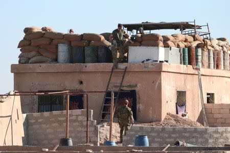 A U.S. fighter walks down a ladder from a barricade, north of Raqqa city, Syria, November 2016. REUTERS/Rodi Said