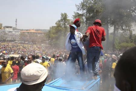 Students stand in front of a burning portable toilet during a protest over planned increases in tuition fees at the Union Buildings in Pretoria, October 23, 2015. REUTERS/Sydney Seshibedi