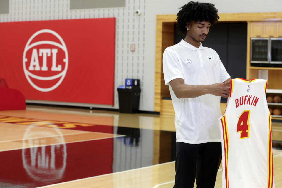 Kobe Bufkin, the 15th overall pick of 2023 NBA draft, looks at his jersey before speaking to the media at the Hawks' NBA basketball training facility in Atlanta, Monday, June 26, 2023. (Natrice Miller/Atlanta Journal-Constitution via AP)