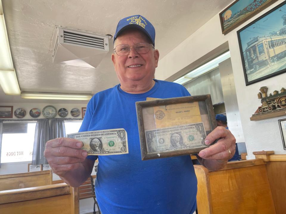 Burger Depot co-owner David Mount displays the first dollar the store earned in 1979 and the last dollar it took in on Thursday.