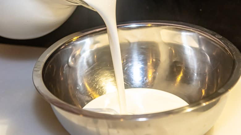 person pouring heavy cream into bowl