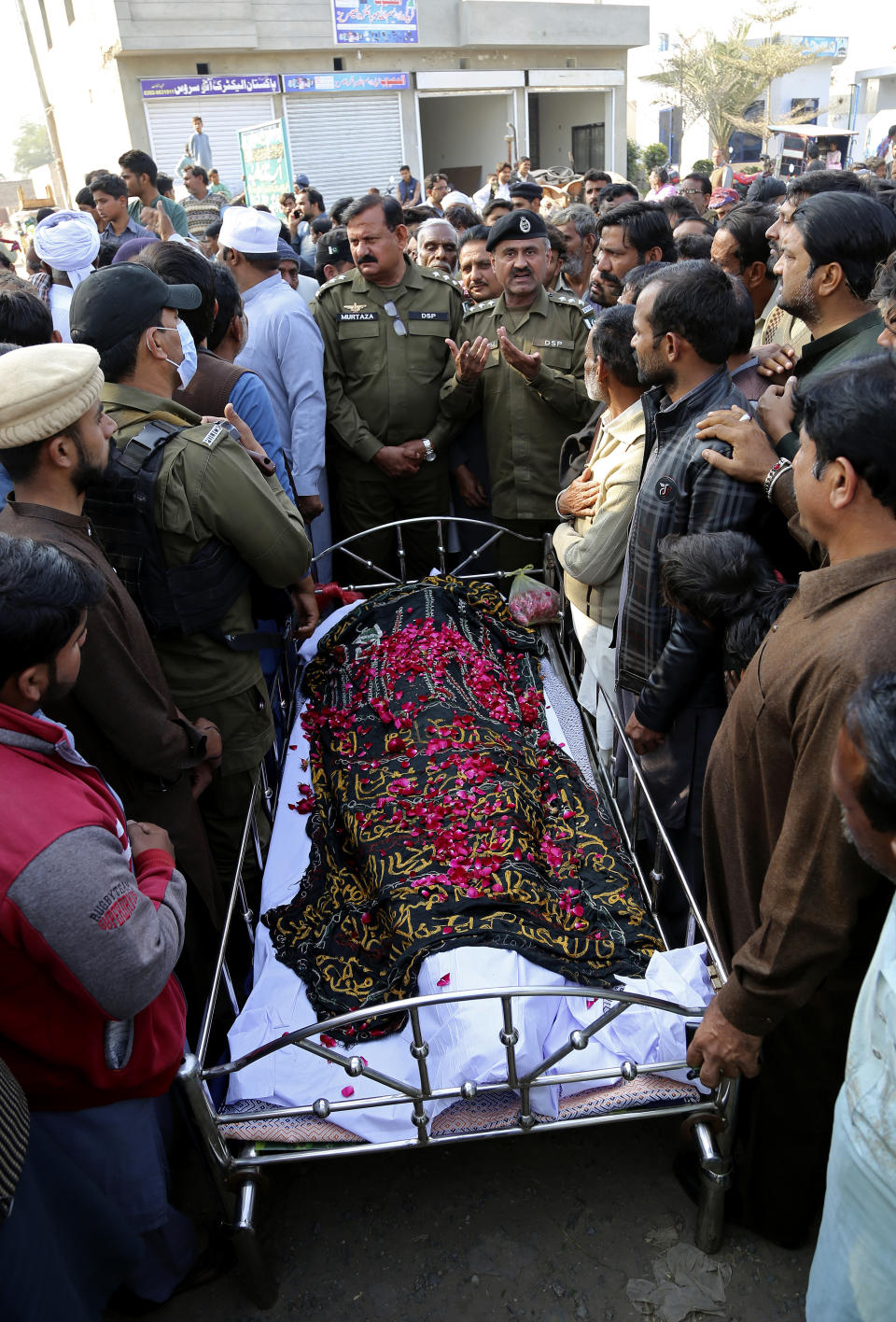 Police officers, relatives and other villagers gather around the body of Mushtaq Ahmed, 41, who was killed when an enraged mob stoned him to death for allegedly desecrating the Quran, during his funeral in Tulamba, a remote village in the district of Khanewal in eastern Pakistan, Sunday, Feb. 13, 2022. Mob attacks on people accused of blasphemy are common in this conservative Islamic nation where blasphemy is punishable by death. (AP Photo/Asim Tanveer)