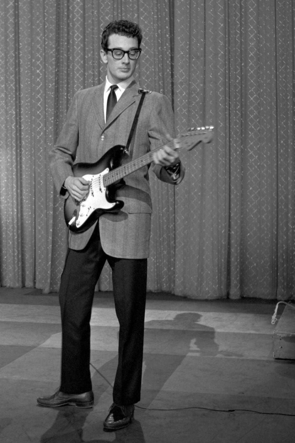 buddy holly plays electric guitar while standing in front of a diamond patterned curtain