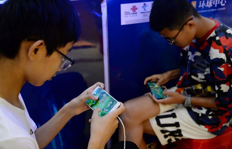 FILE PHOTO: Young people play the game "Honour of Kings" by Tencent, during an event inside a shopping mall in Handan, Hebei