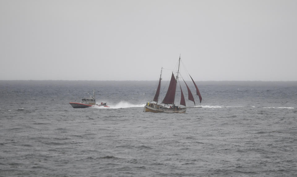 A U.S. Coast Guard boat goes past a sailboat during a search effort near where a boat capsized just off the San Diego coast Sunday, May 2, 2021, in San Diego. (AP Photo/Denis Poroy)