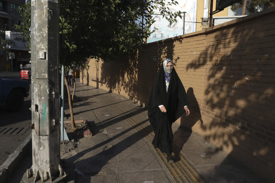 A woman wearing protective face mask to help prevent the spread of the coronavirus walks on a sidewalk in southern Tehran, Iran, Tuesday, July 20, 2021. Iran on Tuesday broke another record in the country's daily new coronavirus cases, even as Tehran and its surroundings went into lockdown, a week-long measure imposed amid another surge in the pandemic. (AP Photo/Vahid Salemi)