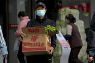 A man wearing a face mask carries a box with groceries as he leaves a supermarket in Beijing, Sunday, Nov. 27, 2022. Protests against China's strict zero-COVID policies in Shanghai continued on Saturday afternoon, after police cleared away hundreds of protesters in the early morning hours with force and pepper spray. (AP Photo/Andy Wong)