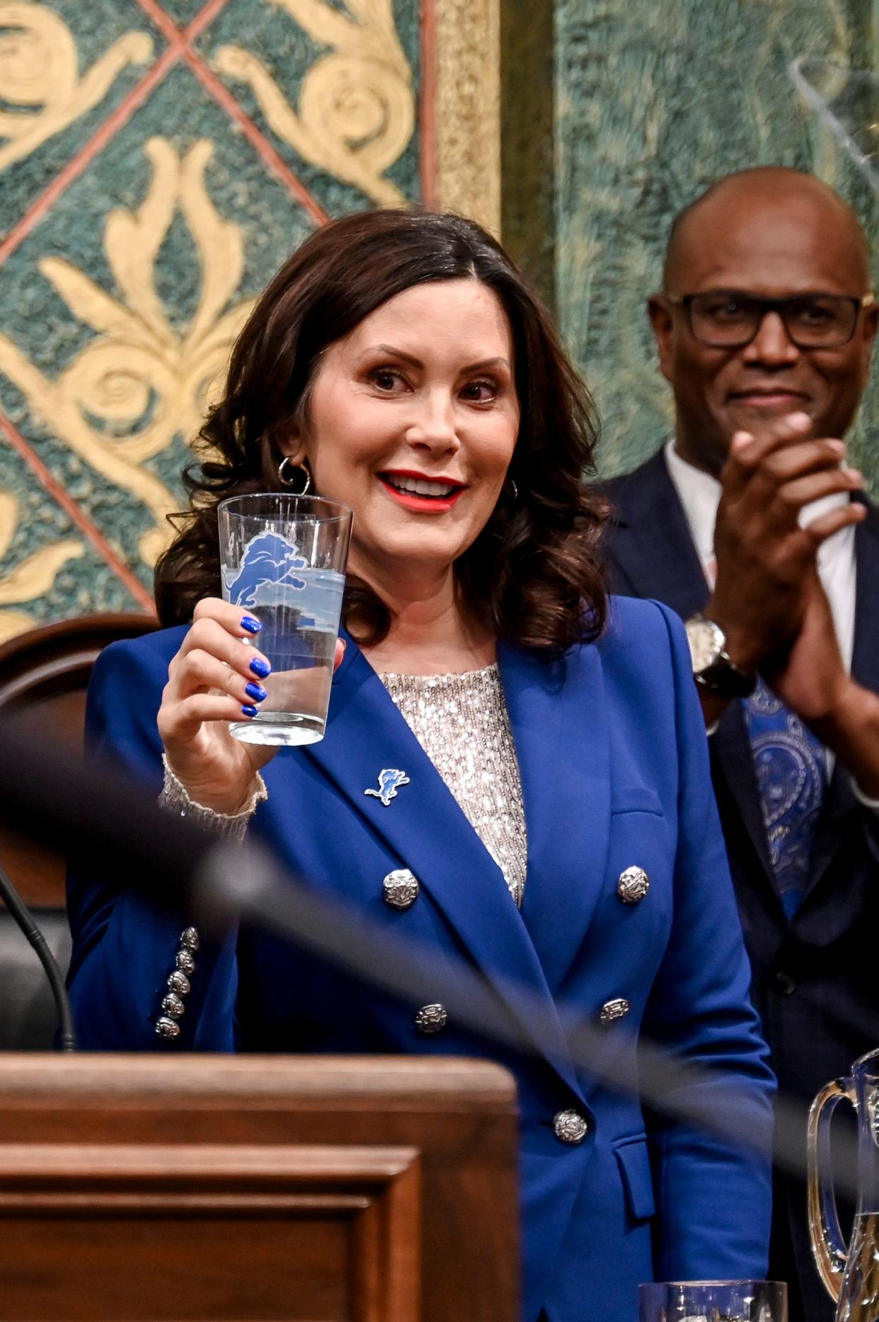 Gov. Gretchen Whitmer holds up a cup with the Lions logo on it before delivering her State of the State address on Wednesday, Jan. 24, 2024, at the Michigan State Capitol in Lansing.