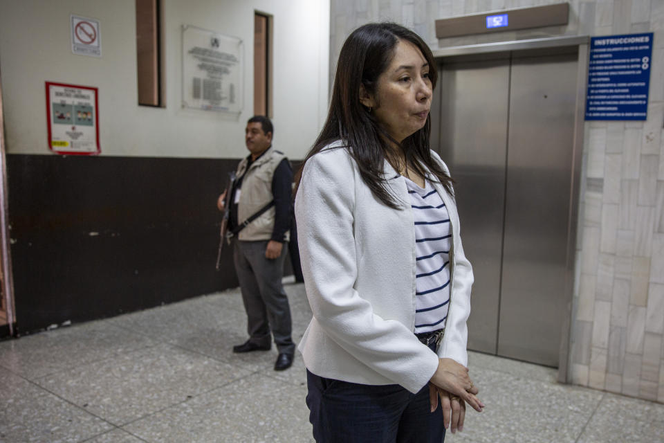 In this Nov. 8, 2019 photo, Guatemalan judge for high risk crimes Erika Aifan talks with a reporter, escorted by a bodyguard outside her courtroom in Guatemala City. Since 2006, the judge has been accompanied by a small group of security guards, some armed with AK-47 assault rifles, wherever she goes. She recently received an armored vehicle to travel in. (AP Photo/Moises Castillo)