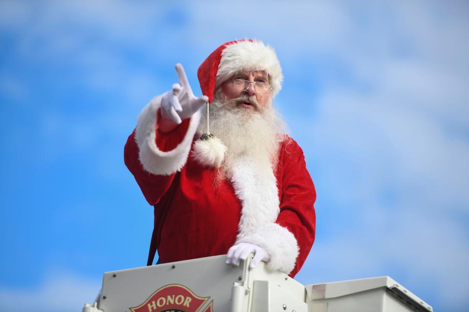 Santa waves to kids as he rides a firetruck in Augusta's Christmas Parade down Greene Street and Telfair Street on Saturday, Dec. 9, 2023.