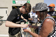 Callum Ilott, of England, signs an autograph for a fan during practice for the Indianapolis 500 auto race at Indianapolis Motor Speedway, Friday, May 20, 2022, in Indianapolis. (AP Photo/Darron Cummings)