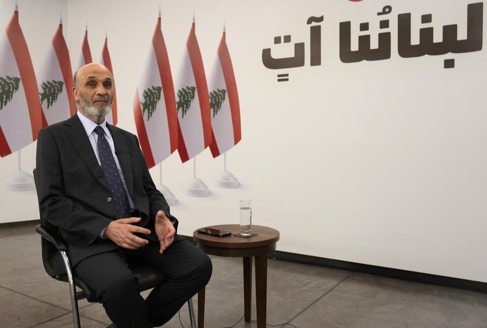 Samir Geagea, leader of the Christian Lebanese Forces party, speaks during an interview with the Associated Press, in Maarab east of Beirut, Tuesday, April 30, 2024. Geagea blasted the Shiite militant group Hezbollah for opening a front with Israel to back up its ally Hamas, saying it has harmed Lebanon without making a dent in Israel's crushing offensive in the Gaza Strip. The Arabic words on the wall read:"Our Lebanon is coming." (AP Photo/Hussein Malla)