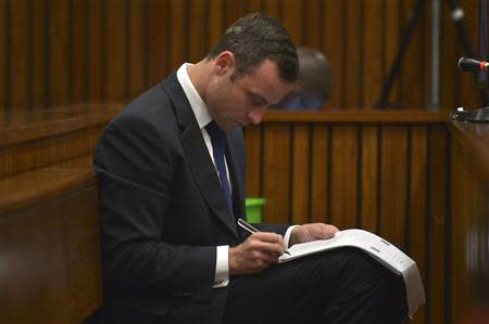 Olympic and Paralympic track star Oscar Pistorius takes notes during court proceedings at the North Gauteng High Court in Pretoria March 12, 2014. REUTERS/Alexander Joe/Pool