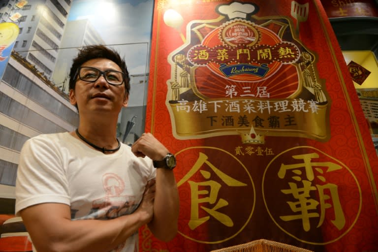 Ah Tong, a Hong Kong emigrant to Taiwan, stands next to a banner showing his award in a Kaohsiung culinary competition, at his restaurant in the Shihlin night market in Taipei