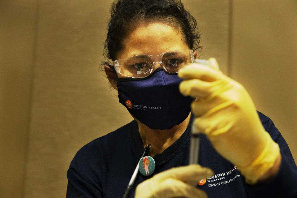 Houston Health Department LVN Alicia Meza prepares a dose of COVID-19 vaccine Sunday, Jan. 3, 2021, at a Houston Health Department's COVID-19 vaccine clinic in Houston. The department vaccinated 1,008 people who qualify under Phase 1A or Phase 1B of the state's guidelines at the clinic's first day on Saturday. (Yi-Chin Lee/Houston Chronicle via AP)