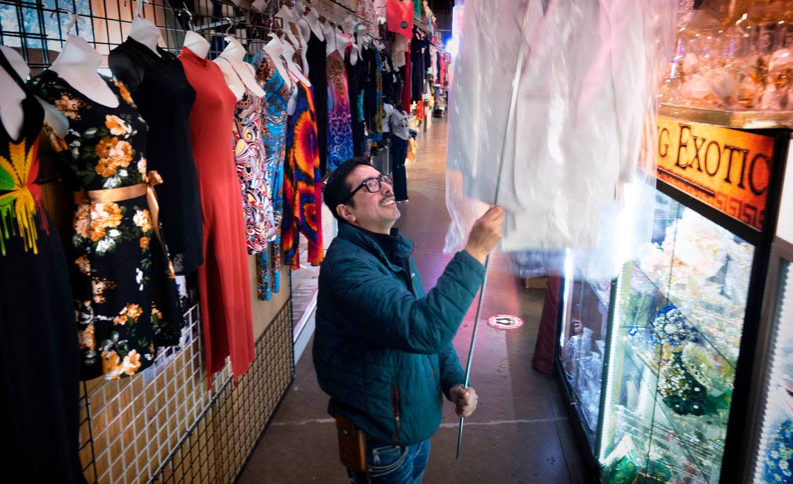 Ricardo Garcia pulls down dresses at his Cascabel Western Wear shop at Tacoma Discount World in Lakewood, Washington, on Wednesday, Jan. 18, 2023. The building that hosts cooperative family markets will close at the end of April.