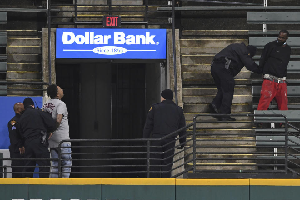 Two people who were apparently unauthorized to be in the stadium grounds are taken into custody by Cleveland police officers during the fifth inning of Game 2 of an American League wild-card baseball series between the New York Yankees and Cleveland Indians, Wednesday, Sept. 30, 2020, in Cleveland. (AP Photo/David Dermer)