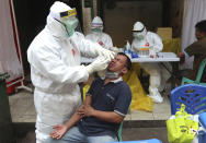 A health worker takes a nasal swab sample from a man during a public testing for the coronavirus conducted at a market in Jakarta, Indonesia, Friday, May 29, 2020.(AP Photo/Achmad Ibrahim)