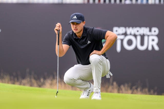 Ludvig Aberg crouches to line up a putt