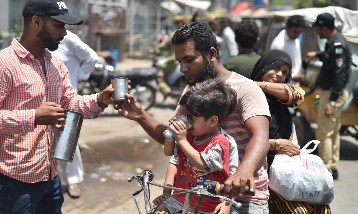 <span>A Pakistani security official offers cold drinks to people in Karachi.</span><span>Photograph: Shahzaib Akber/EPA</span>