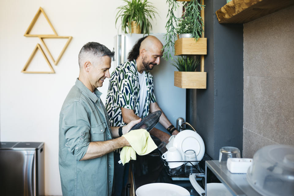 Mid adult gay couple washing dishes together in a kitchen