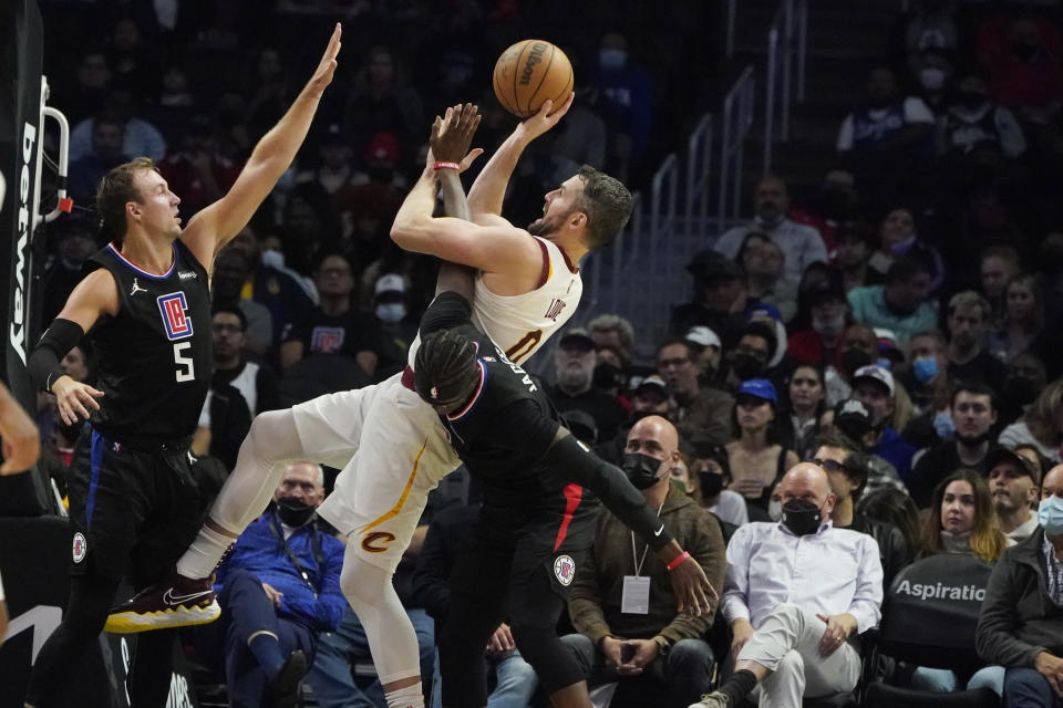 Cleveland Cavaliers forward Kevin Love, center, shoots between Los Angeles Clippers guard Luke Kennard (5) and guard Reggie Jackson during the second half of an NBA basketball game Wednesday, Oct. 27, 2021, in Los Angeles. (AP Photo/Marcio Jose Sanchez)