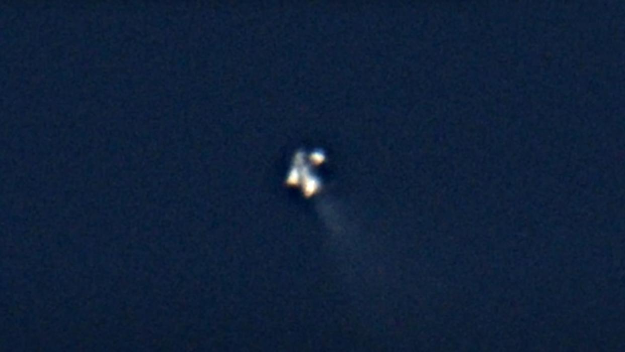  A highly zoomed-in view of a silver rocket in the upper atmosphere. 