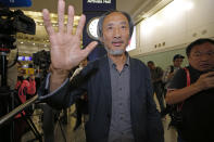 Chinese dissident writer Ma Jian waves to media after arriving Hong Kong international airport, Friday, Nov. 9, 2018. Despite Mallet's rejection, Hong Kong on Friday permitted dissident writer Ma Jian to enter to attend a literary festival, even after an arts venue in the city canceled his appearance. Ma, whose novels frequently satirize China's communist leaders, told reporters he experienced nothing unusual while passing through passport control and that organizers were still lining-up a place for him to speak. "The lecture will definitely happen. If there is a single Hong Kong person who is willing to listen, or a single reader who contacts me, I will be there," Ma said. (AP Photo/Kin Cheung)