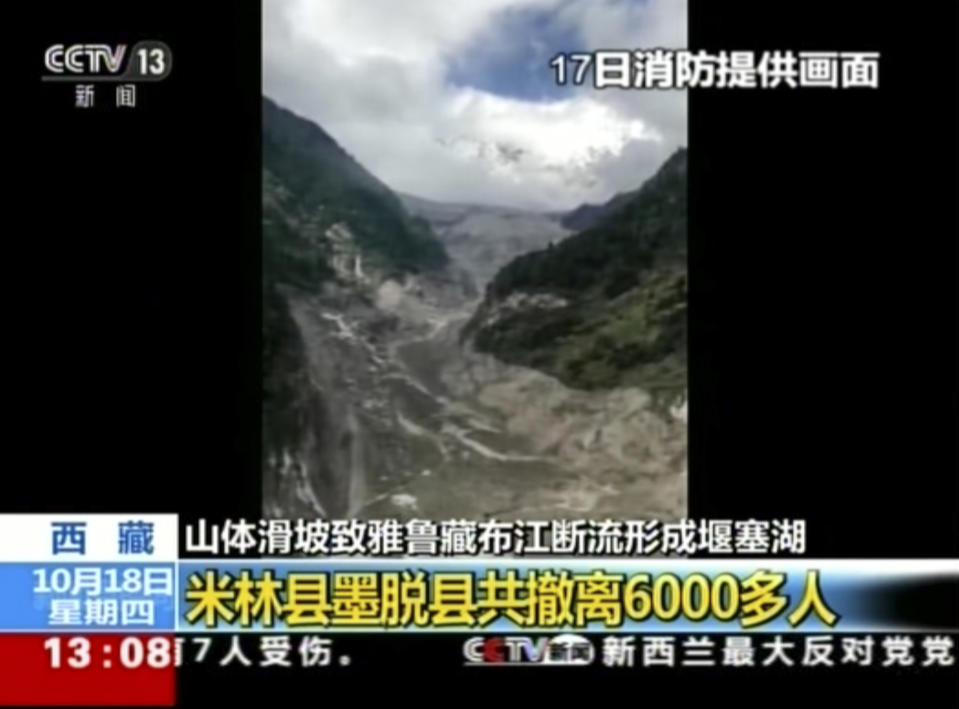 In this image taken from video footage run on Thursday, Oct 18, 2018, by China's CCTV via AP Video, a view of the landslide and barrier lake is seen on Yarlung Tsangpo in Tibet in western China. Thousands of people have been evacuated following a landslide in Tibet that blocked the flow of one of the region's key rivers, China's emergency services said Thursday. Headlines in Chinese reads: "Oct. 17 footage provided by firefighter" "around 6,000 people evacuated." (CCTV via AP Video)