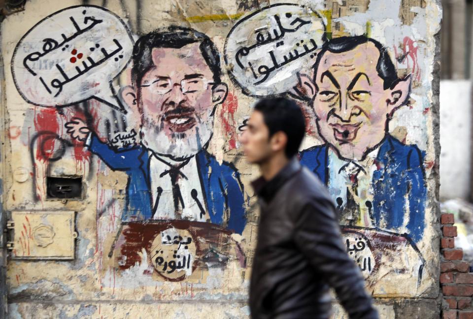 A protester walks past a graffiti during a march at Tahrir Square in Cairo. The arabic words read, "After the revolution - let them speak" (L), "Before the revolution - let them play" (R) (Reuters)