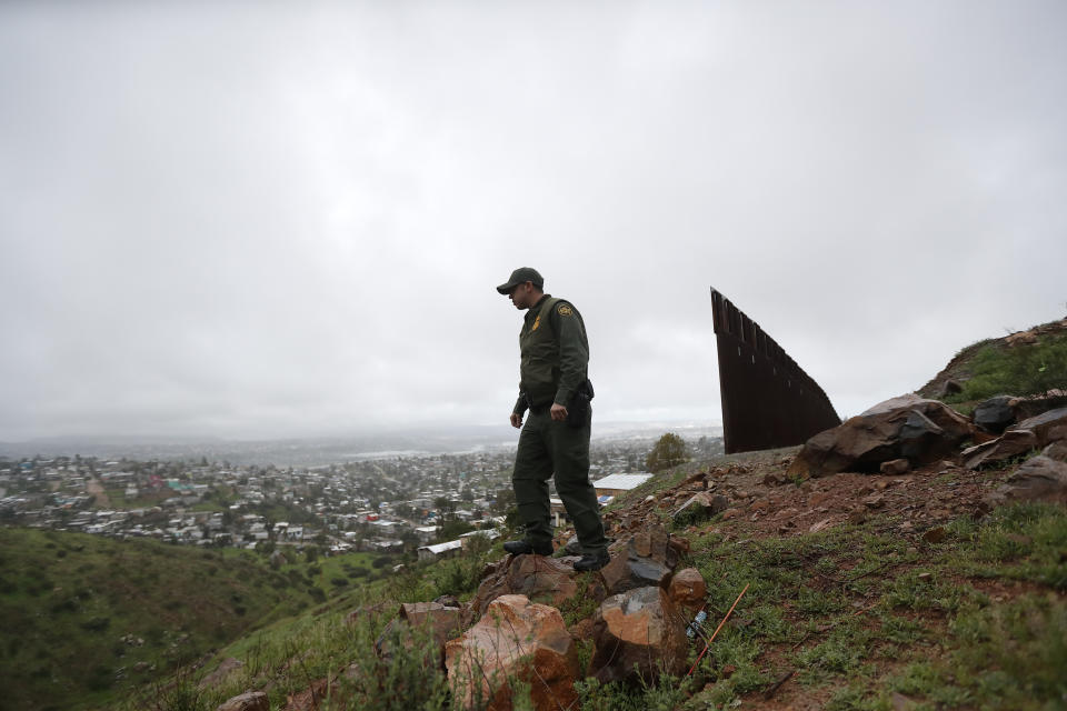 FILE - In this Feb. 5, 2019, file photo, Border Patrol agent Vincent Pirro looks on near where a border wall ends that separates the cities of Tijuana, Mexico, left, and San Diego, in San Diego. The government is working on replacing and adding fencing in various locations, and Trump in February declared a national emergency to get more funding for the wall. (AP Photo/Gregory Bull, File)