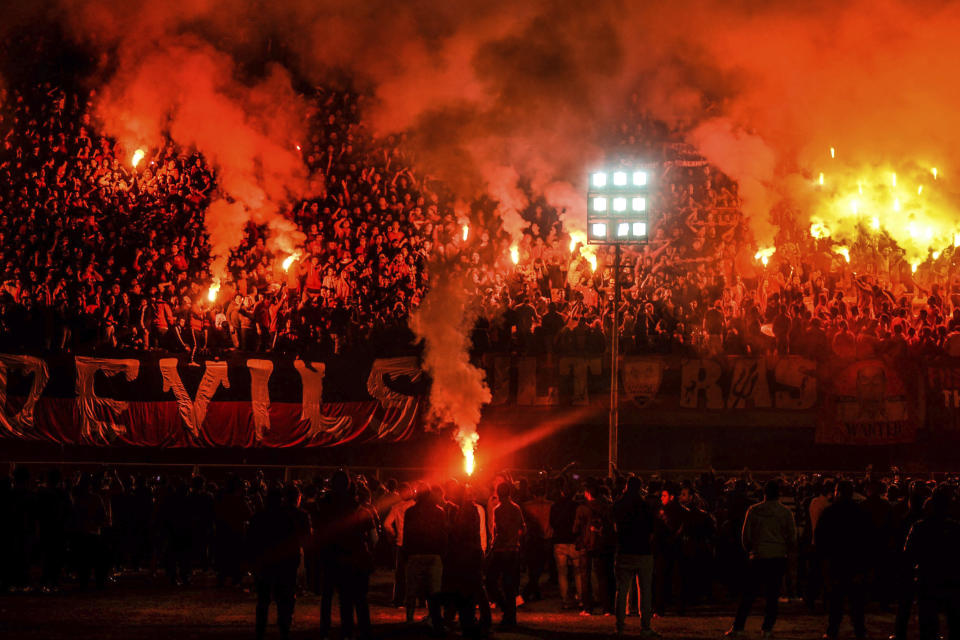 FILE - In this Feb. 1, 2015 file photo, hardcore soccer fans known as Ultras Ahlawy, light flares and cheer as they mark the third anniversary of some 70 people who were killed in a 2012 soccer riot in Port Said, at Al -Ahly Sporting Club in Cairo, Egypt. Egypt’s close relations with Saudi Arabia are being tested by a soccer spat sparked by an uproar over meddling by the kingdom’s sports minster, Turki al-Sheikh. The ongoing upheaval is destabilizing soccer in Egypt as it tries to shake off memories of the national team’s group-stage exist at the World Cup in June and the deaths of nearly 100 fans this decade. (AP Photo/Mohammed El Raai, File)