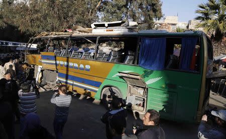 Members of Syrian security services and journalists look at the wreckage of a bus on which an explosion occurred, in central Damascus February 1, 2015. REUTERS/Omar Sanadiki