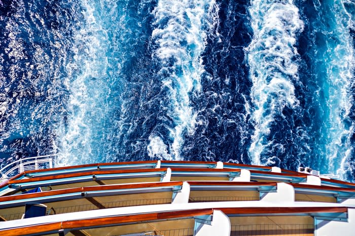 The large wake of a cruise ship is seen from the top of the ship.