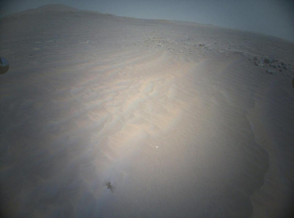 The shadow of Ingenuity, Nasa’s Mars helicopter, can be seen to the lower left as the vehicle soars above the Martian landscape (Nasa)