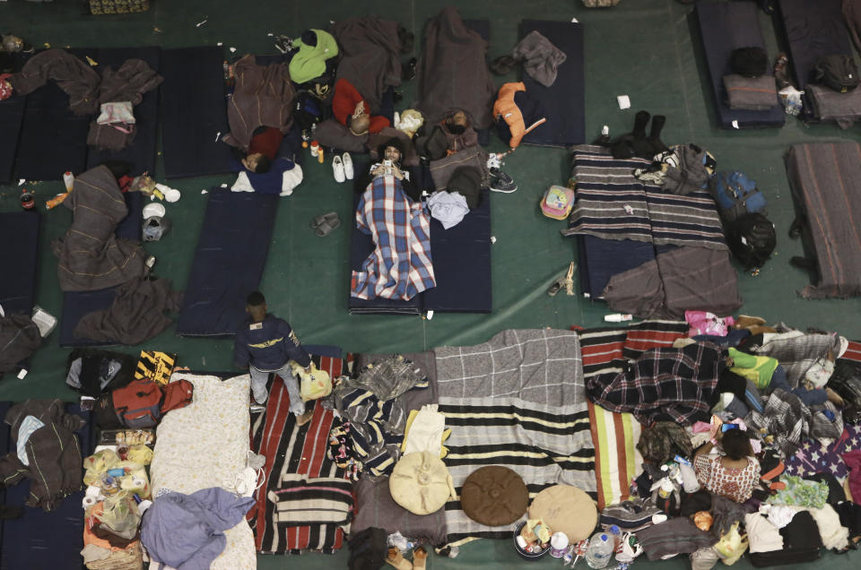 In this Tuesday, Feb. 19, 2019 photo, migrants from Central America, Africa and the Caribbean, who are awaiting their turns to request asylum in the U.S., pass the time inside a shelter in Bachilleres gymnasium in Ciudad Juarez, Mexico. Hundreds of migrants, some of whom arrived from the recently closed shelter in Piedras Negras on the Mexico-U.S. border, are camped out in the gym waiting their chance to submit their asylum request at the El Paso port of entry. (AP Photo/Christian Torres)