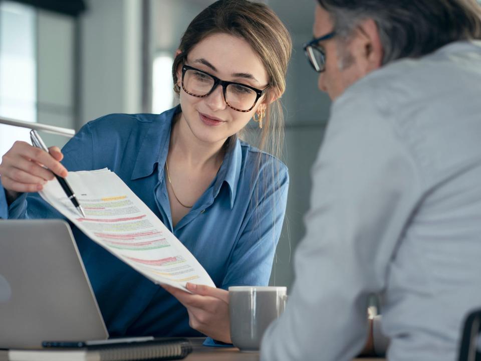 An accountant reviews tax paperwork over a laptop with a client.