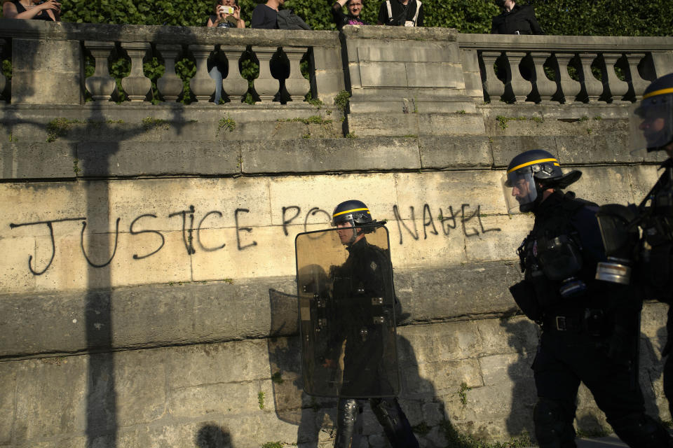 ARCHIVO - Policías patrullando junto a un graffiti que dice "Justicia para Nahel" mientras varios jóvenes se reúnen en la Plaza de la Concordia durante una protesta en París, Francia, el viernes 30 de junio de 2023. (AP Foto/Lewis Joly, Archivo)