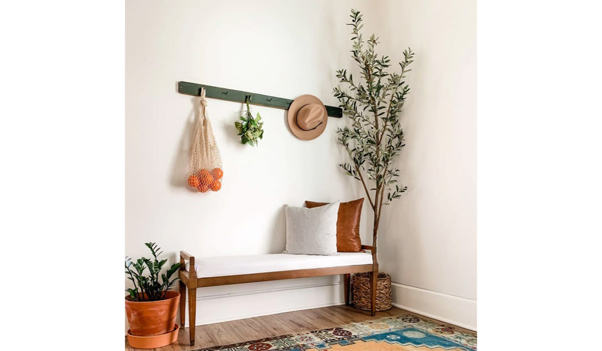 Faux olive tree next to bench in entryway