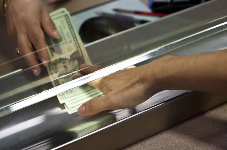 Money being put in the slot under a clerk's window