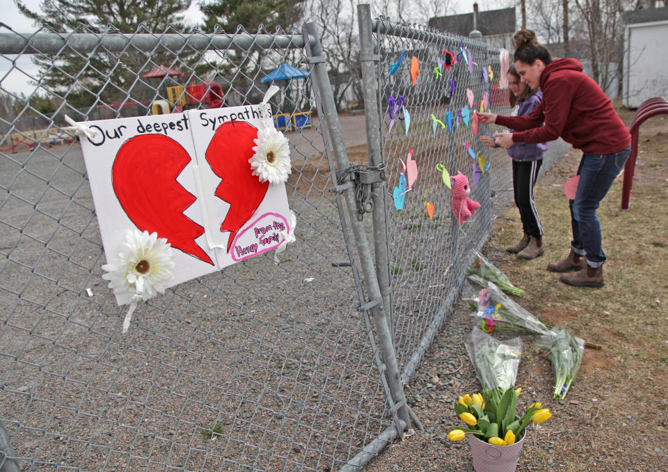 DEBERT, NS - APRIL 20:  A woman and her daughter place a heart on a fence at a growing memorial in front of the Debert School April 20, 2020 in Debert, Nova Scotia, Canada. Lisa McCully, a teacher at the school, was one of 19 people killed during Sunday's shooting rampage, including the gunman. The rampage, which was Canada's worst mass killing, began Saturday night in Portapique, and continued through other rural communities in the Maritime Provinces. (Photo by Tim Krochak/Getty Images)