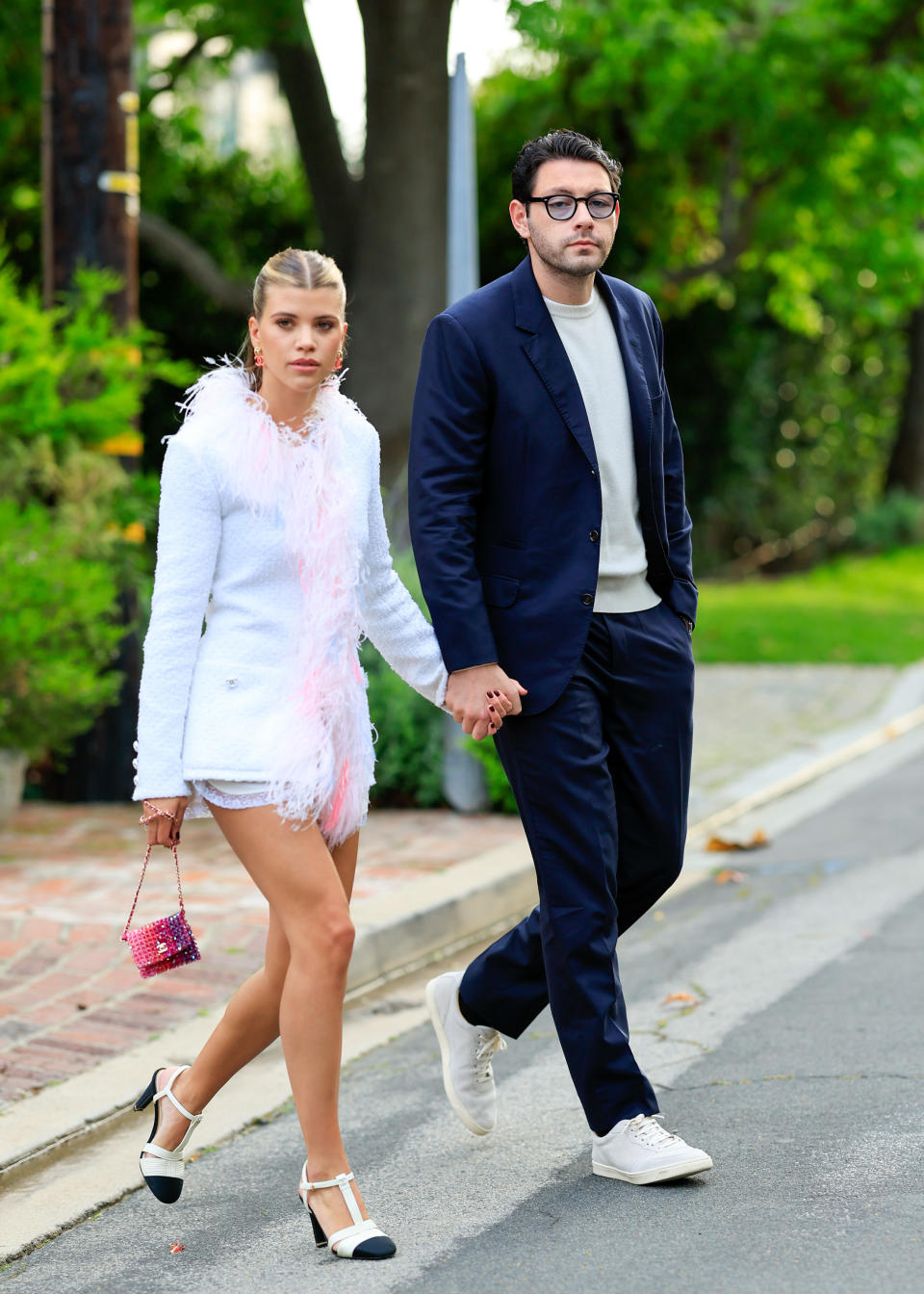 sophia and elliot holding hands as they cross a street