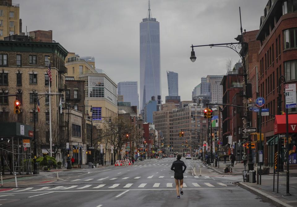 Una persona corre en solitario en 7th Avenue, que luce parcialmente vacía a raíz de las restricciones impuestas por las autoridades que piden a los habitantes a mantenerse en casa y respetar un distanciamiento social para frenar la propagación del COVID-19, el sábado 28 de marzo de 2020, en Nueva York. (AP Foto/Bebeto Matthews)